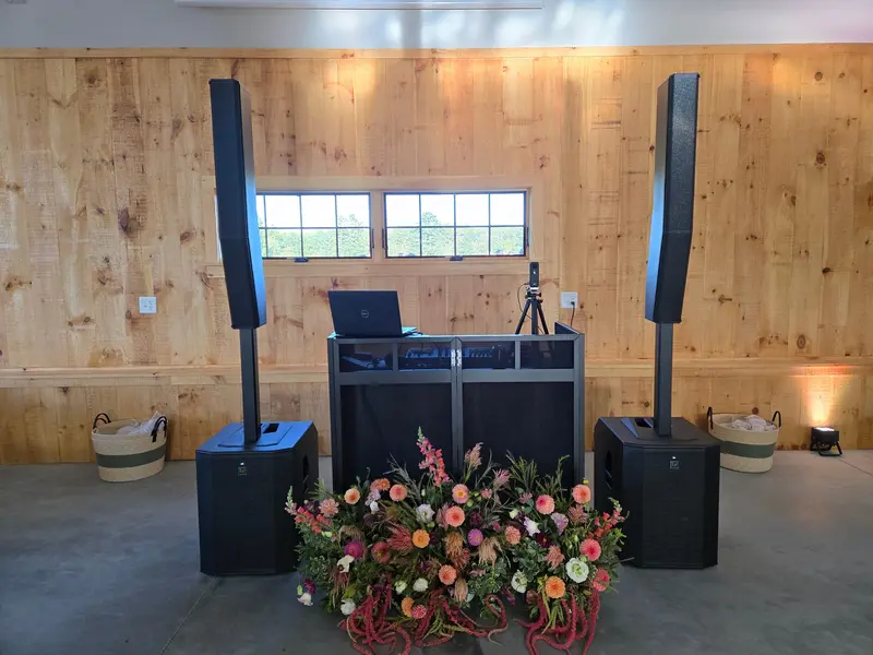 DJ setup in a rustic barn venue with natural wood walls and floral arrangement