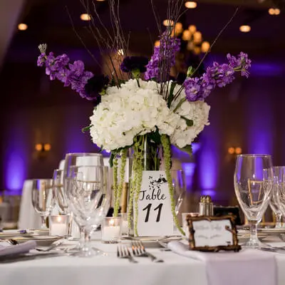 Wedding table centerpiece with purple uplighting